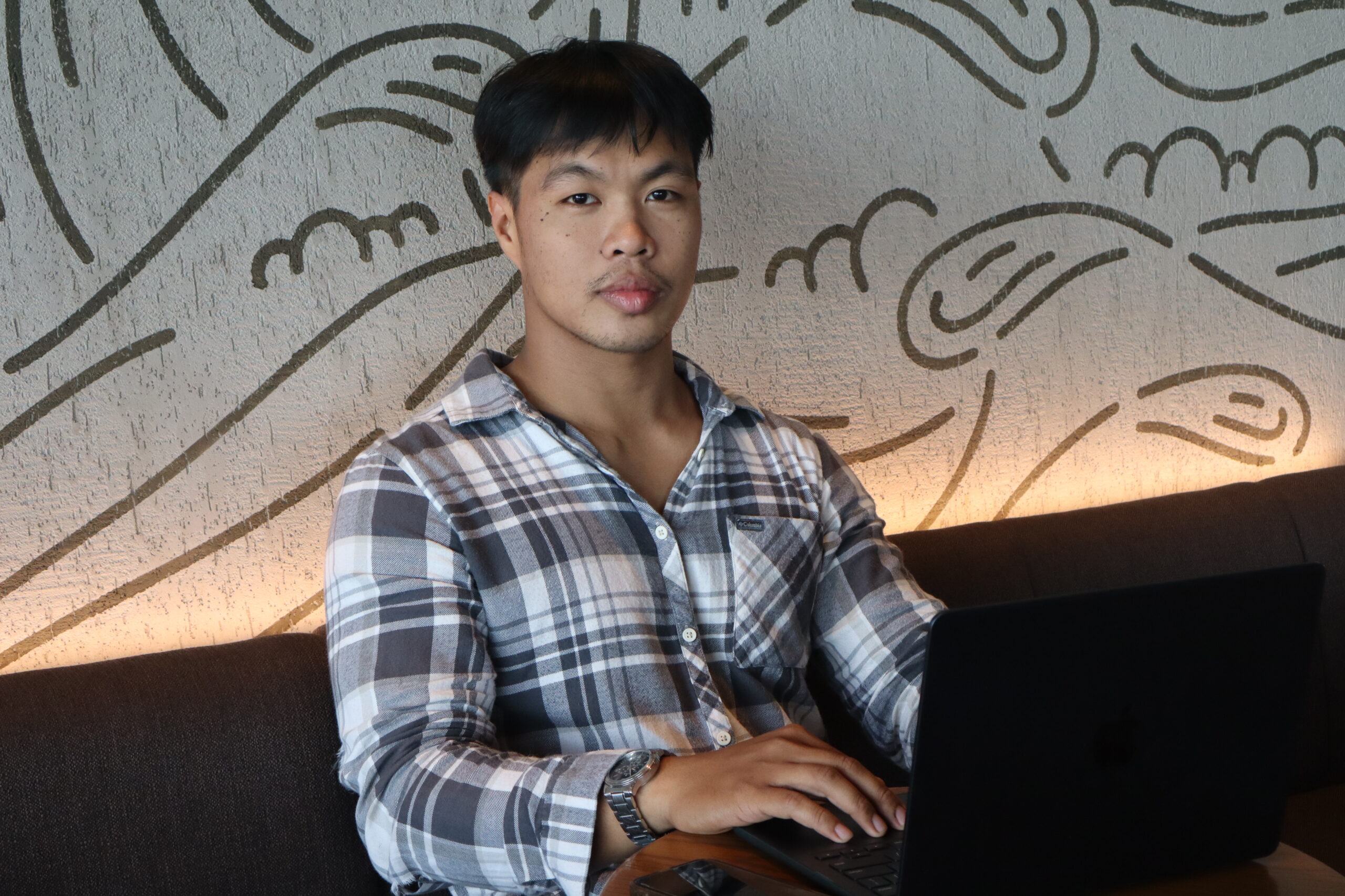 Axl Troy Dacquel, Co-founder and Operations Director, sitting on a sofa with a laptop