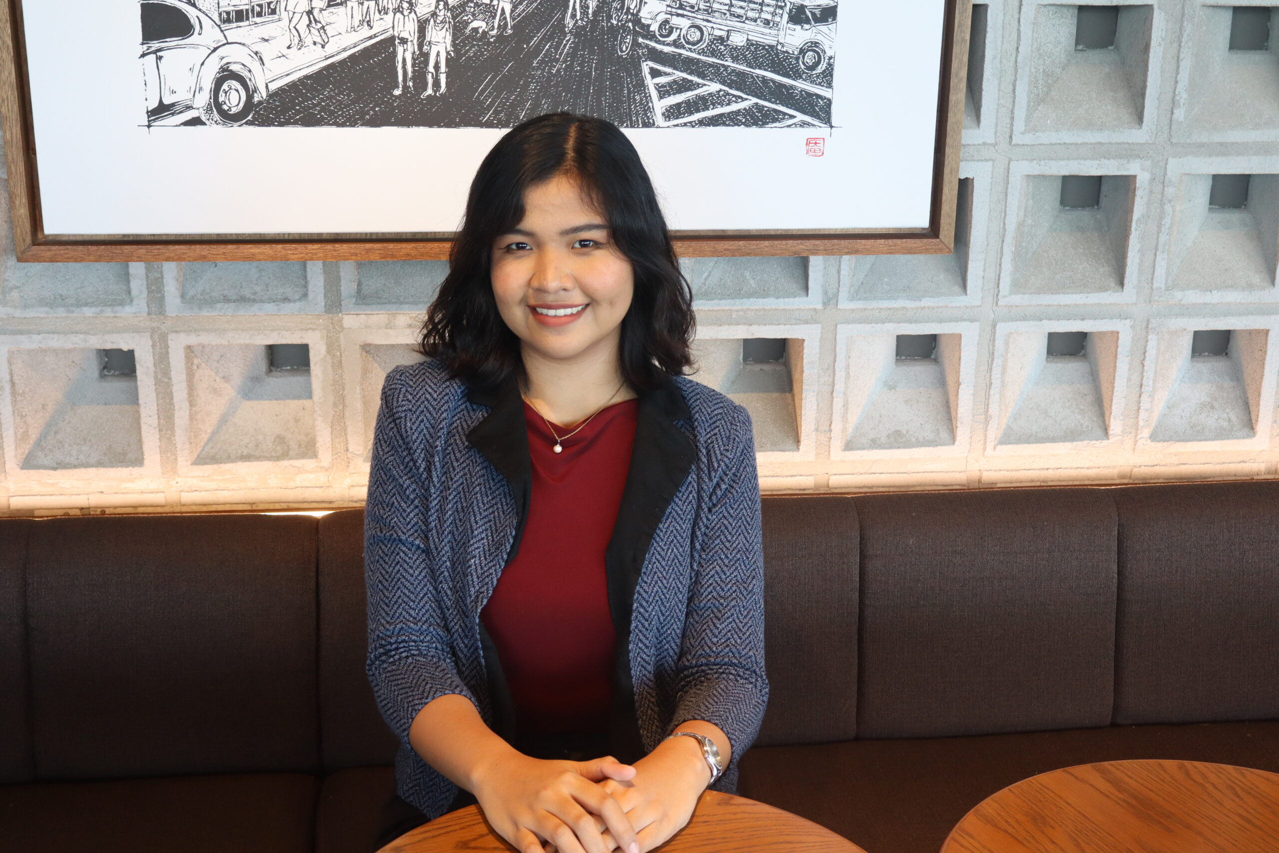 Shiela De La Cruz, Founder and Managing Director of Anchor Growth Co, smiling while sitting on a chair 