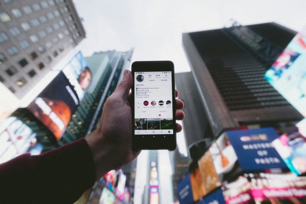 a hand holding a phone high up with buildings showing in the background