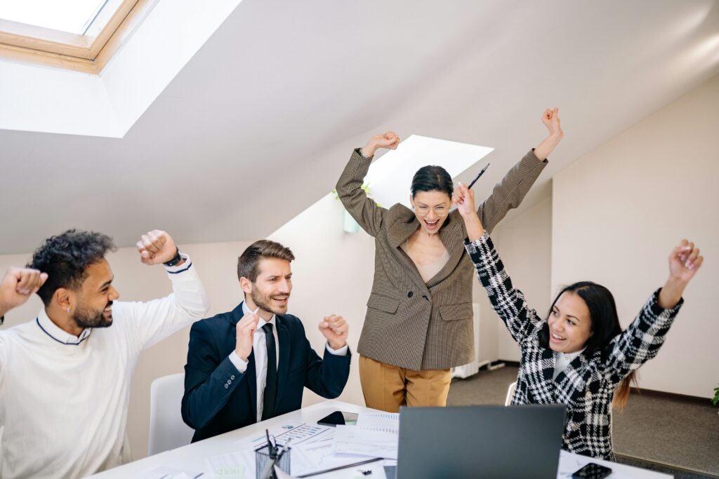 Four people celebrating in an office after a successful marketing strategy