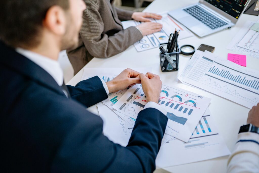 a shoulder shot of people in a meeting and papers showing performance metrics