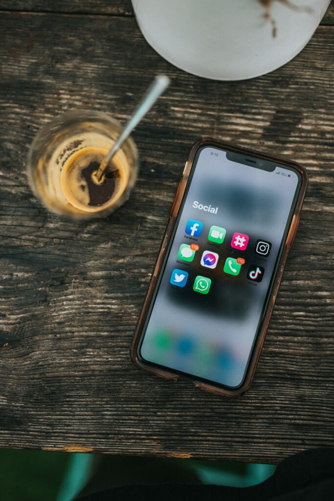 Smartphone showing social media apps next to a coffee