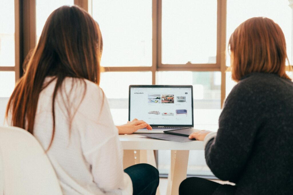 Two women reviewing a new client’s onboarding plan on a laptop