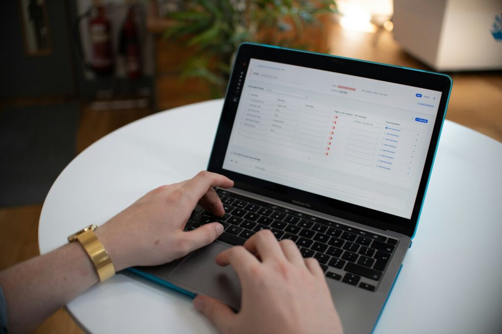 Hands typing on a laptop with a spreadsheet open on the screen