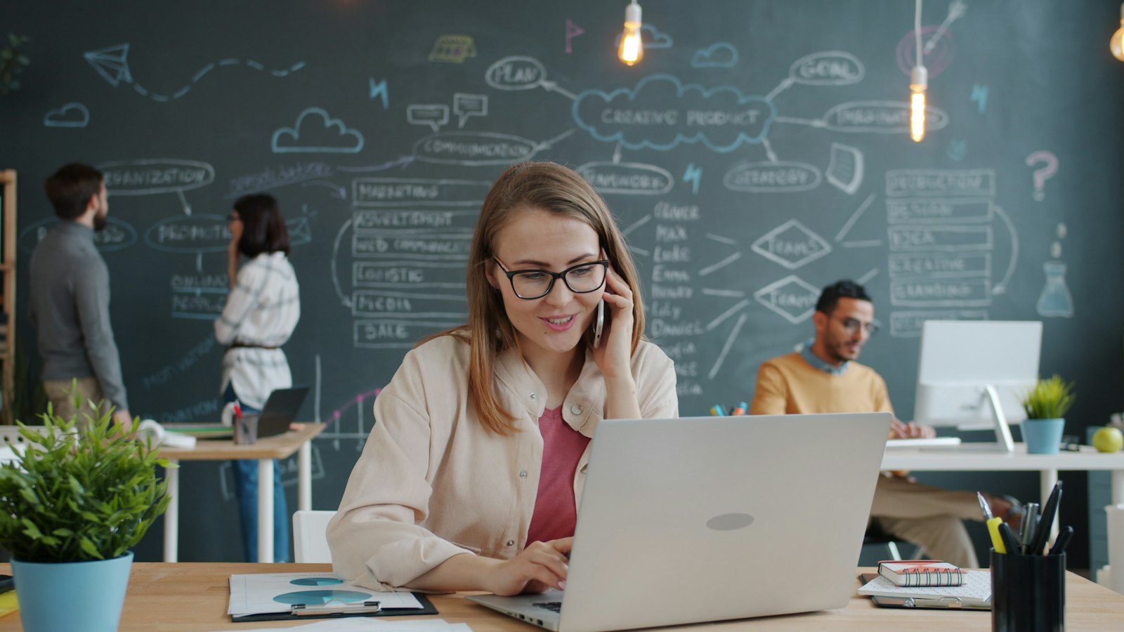 A woman answering a phone call from a new lead while working on her laptop