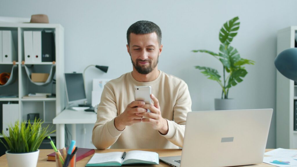 A business owner reading a new enquiry on his phone at his desk